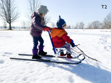Girl and Boy riding ESLA T2 blue kicksled on the packed snow at Wind Point Lighthouse in Racine, Wisconsin